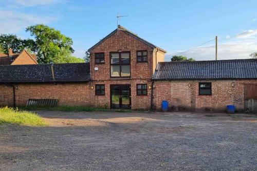 un antiguo edificio de ladrillo rojo con una gran ventana en Hillfields Farm Barn - A Rural Equestrian Escape, en Coventry