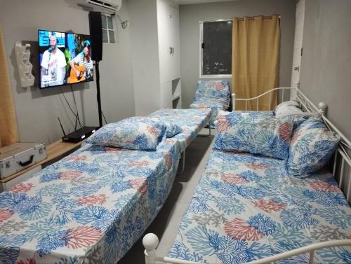 two beds in a hospital room with a tv at Dimbar Tech in Pasong Mannga