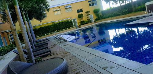 San Pedro的住宿－Hantowah's Crib - Southwoods，一座棕榈树游泳池,位于酒店大楼旁