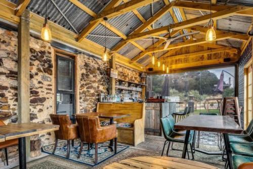 a restaurant with wooden ceilings and tables and chairs at Blacksmith Cottage Aldinga in Aldinga