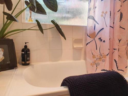 a bathroom with a bath tub and a bottle of wine at Eden on Young Street in Wayville