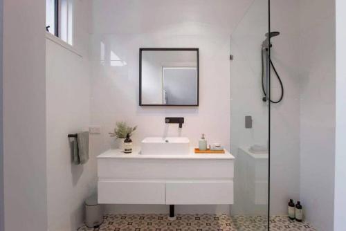 een witte badkamer met een wastafel en een spiegel bij Morris Cottage Cumberland Park in Colonel Light Gardens