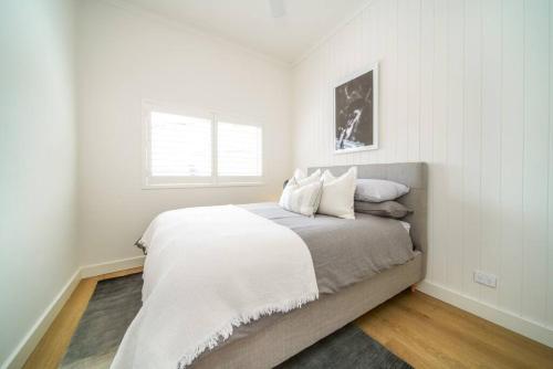a white bedroom with a bed with white sheets and a window at The Retreat Plympton in Plympton