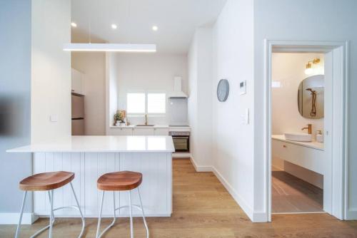 a kitchen with a white counter and two stools at The Retreat Plympton in Plympton