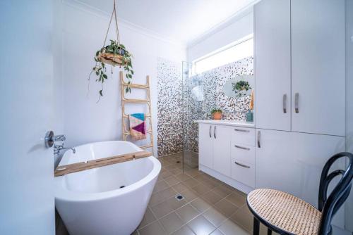 a bathroom with a tub and a table and a chair at Il Cappano Rosa Henley Beach in Grange