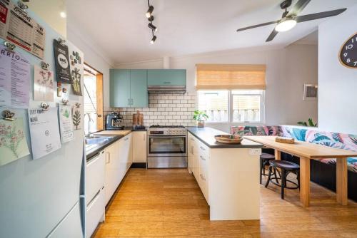 a kitchen with white cabinets and a wooden table at Il Cappano Rosa Henley Beach in Grange