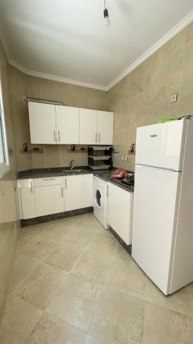 La cuisine est équipée de placards blancs et d'un réfrigérateur blanc. dans l'établissement tetouan wilaya, à Tetouan