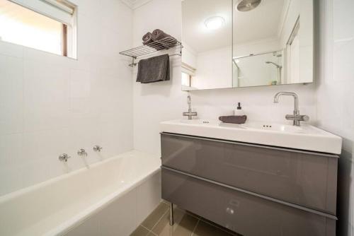 a bathroom with a sink and a tub and a mirror at Emerald on Gover Street in Bowden