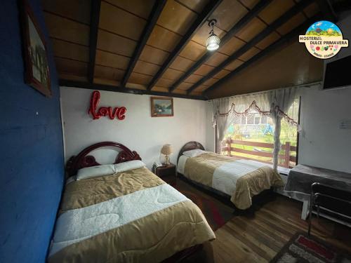 a bedroom with two beds and a love sign on the wall at Hotel Dulce Primavera in Ambato