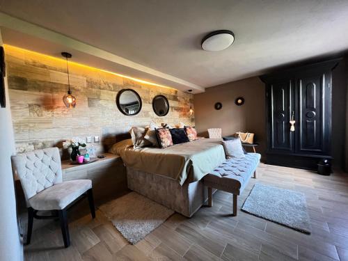 ein Schlafzimmer mit einem Bett und zwei Stühlen und Spiegeln in der Unterkunft DEPARTAMENTO VILLA NEEK in San Cristóbal de las Casas