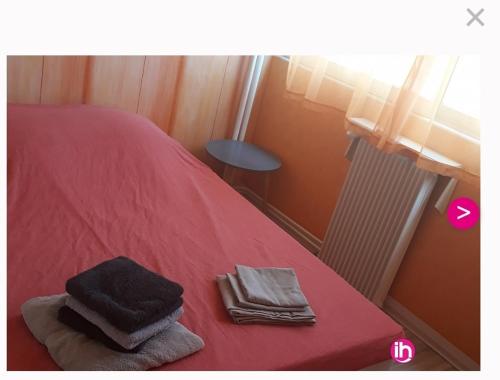 - un lit rouge avec des serviettes assises au-dessus dans l'établissement appartement proche centre ville et gare, à Chalon-sur-Saône