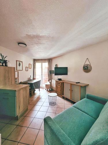 uma sala de estar com um sofá verde e uma televisão em L'Oxalys Studio ! Coin montagne - Pied des pistes & Centre ville em Briançon