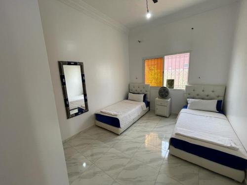 1 dormitorio con 2 camas y espejo. en Villa avec piscine ( régions de Marrakech), 
