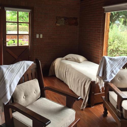 um quarto com uma cama, uma cadeira e uma janela em Cabaña Las dos Marías em Sierra de los Padres