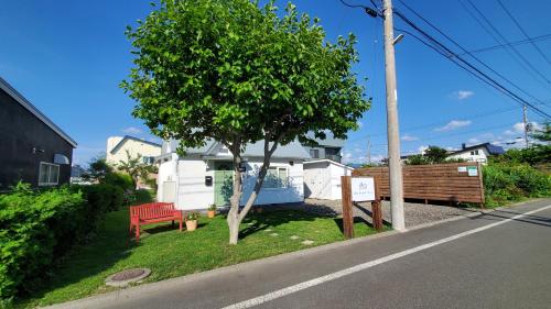 a tree and a red bench on the side of a street at Biei Central Villa - Green Garden in Biei