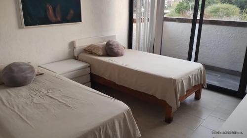 two beds in a room with a window at Caleta in Acapulco