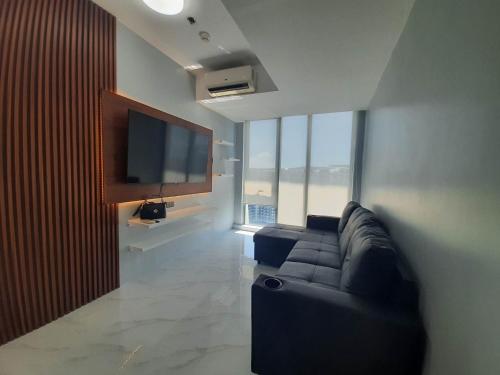 a living room with a couch and a flat screen tv at Beach Front Living in the Heart of the City, AZURE Residences in Manila