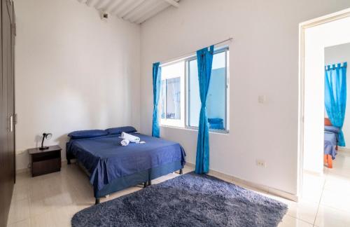 a bedroom with a bed and a window with blue curtains at Hermoso Apartamento en Mesitas de El Colegio in El Colegio