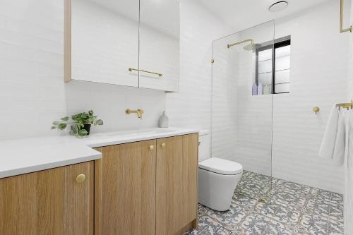 Baño blanco con aseo y lavamanos en Ultimo l Renovated 2 Bedroom House With Rooftop Balcony en Sídney