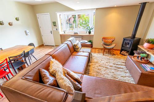 sala de estar con sofá de cuero marrón y estufa de leña en Sua Casa em Canela, en Canela