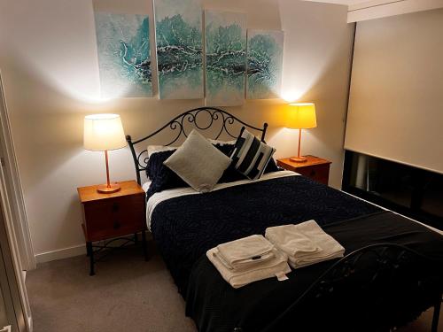 a bedroom with a bed with two lamps and towels on it at Urban Eden in South Yarra in Melbourne
