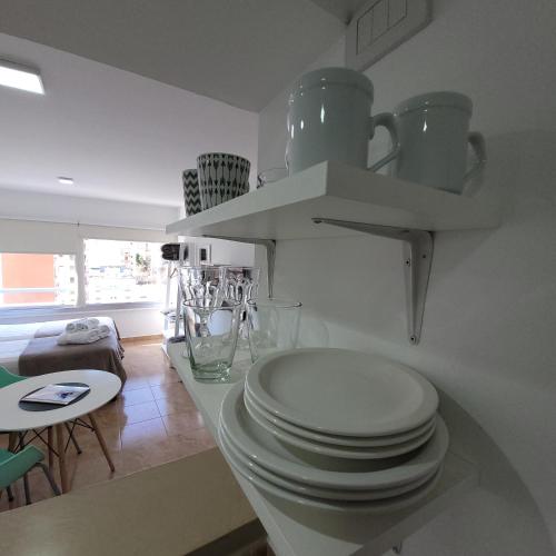 a white kitchen with a stack of plates on a counter at Calle 10 - Monoambiente in La Plata