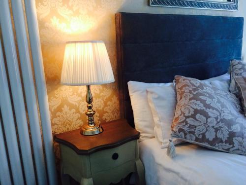 a lamp on a night stand next to a bed at Serendipity House in Derry Londonderry