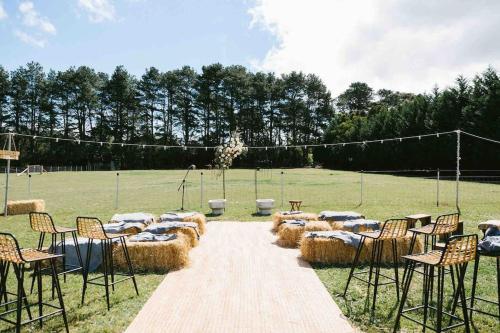 a group of hay bussed tables and chairs in a field at The Maple Lodge with Alpacas, Goats, Boars, Ducks & Chickens Farm Stay with Outdoor Pizza Oven in Robertson