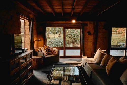 a living room with a couch and a glass table at The Maple Lodge with Alpacas, Goats, Boars, Ducks & Chickens Farm Stay with Outdoor Pizza Oven in Robertson