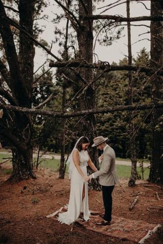 a bride and groom holding hands in a forest at The Maple Lodge with Alpacas, Goats, Boars, Ducks & Chickens Farm Stay with Outdoor Pizza Oven in Robertson