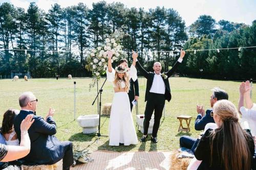 a bride and groom walking down the aisle at their wedding at The Maple Lodge with Alpacas, Goats, Boars, Ducks & Chickens Farm Stay with Outdoor Pizza Oven in Robertson