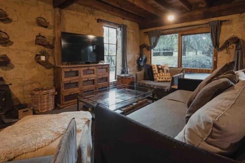 a living room with a couch and a tv at The Maple Lodge with Alpacas, Goats, Boars, Ducks & Chickens Farm Stay with Outdoor Pizza Oven in Robertson