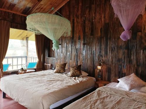 two beds in a room with wooden walls at Mu Cang Chai Eco Lodge in Nam San