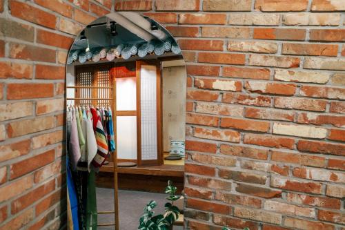 a brick wall with a mirror and a rack of umbrellas at Starria Hostel foreign guest only in Seoul