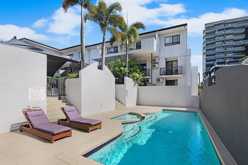 a swimming pool with two chairs and a building at Parkview Apartments in Brisbane