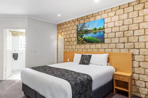 a hotel room with a bed and a brick wall at Great Divide Motor Inn in Toowoomba