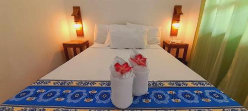 a bed with two vases with red flowers on it at El Taraw Bed & Breakfast in Puerto Princesa City