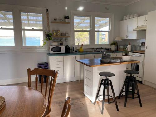 a kitchen with white cabinets and a table and chairs at Windspray Cottage in Port Albert