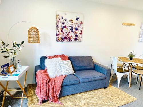 a living room with a blue couch with a blanket on it at Perfect modern Townhouse CBD Christchurch in Christchurch