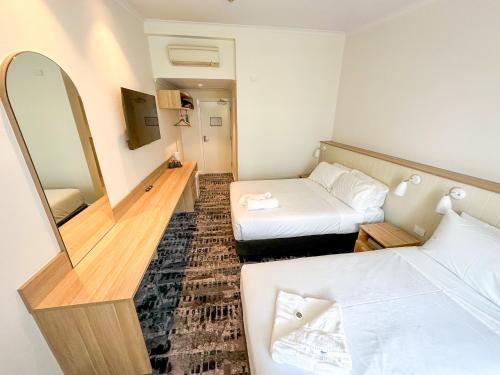 a small room with two beds and a mirror at Pippi's at the Point in Warners Bay