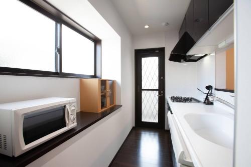 a kitchen with a microwave and a sink and a tub at KS west Waseda 2F in Tokyo