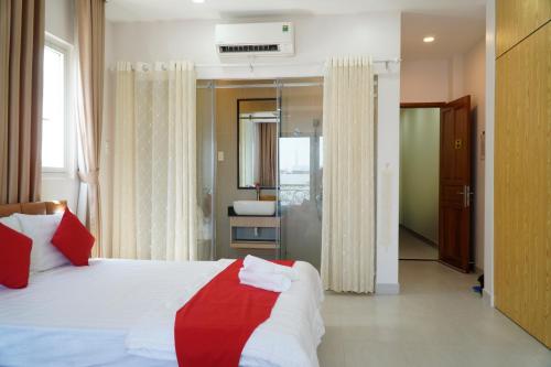 a bedroom with a white and red bed and a bathroom at HOTEL HOA HUỲNH in Ho Chi Minh City