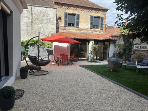 a patio with chairs and a table with a red umbrella at Maison de charme au centre de Moulins, avec jardin et terrasse, tout confort inclus - FR-1-489-474 in Moulins