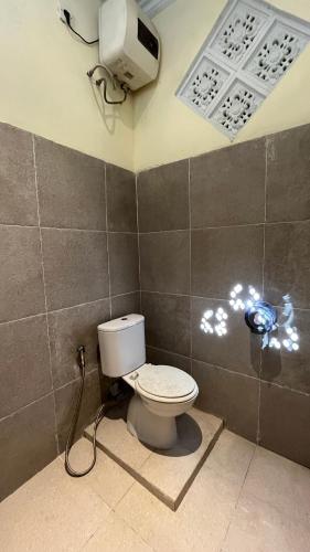 a bathroom with a toilet and a tv on the wall at Puri Jumpungan Villas in Sidemen