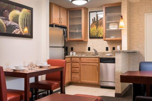 a kitchen with a table and chairs and a kitchen with a refrigerator at Residence Inn Phoenix Desert View at Mayo Clinic in Phoenix