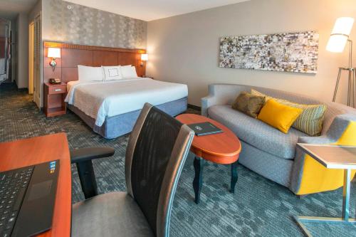 a hotel room with a bed and a couch at Courtyard by Marriott Montgomery Prattville in Prattville