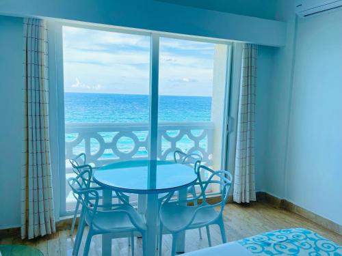 a table and chairs in a room with a view of the ocean at OVA Apartments Cancun in Cancún