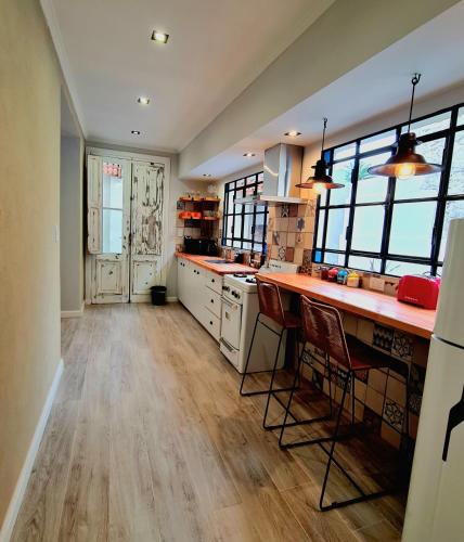 a kitchen with white cabinets and wooden floors and windows at Lechuza Alvear in San Antonio de Areco