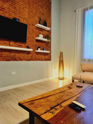 a living room with a wooden table and a brick wall at Lechuza Alvear in San Antonio de Areco