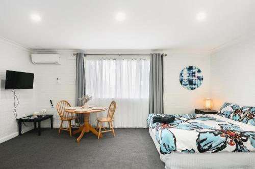 a hotel room with a bed and a table and chairs at Malibu Apartments - Perth in Perth